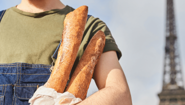 Homme français portant des baguettes de pains proche de la Tour Eiffel